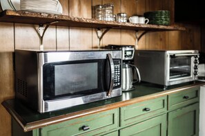 A kitchen with stainless steel appliances, wooden shelves, and green cabinetry. - The Sandbar at Sommer Dorf (West Branch)