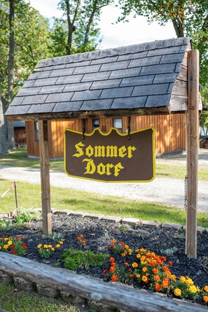 A wooden sign with the text 'Sommer Dorf' mounted on a structure resembling a small house with a sloped roof. - The Sandbar at Sommer Dorf (West Branch)