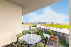 A balcony with a glass table and chairs, a view of a green field, and a building in the distance. - Elegant 2-bedroom suite with private terrace in Pollenzo, Langhe and Roero (Pollenzo)