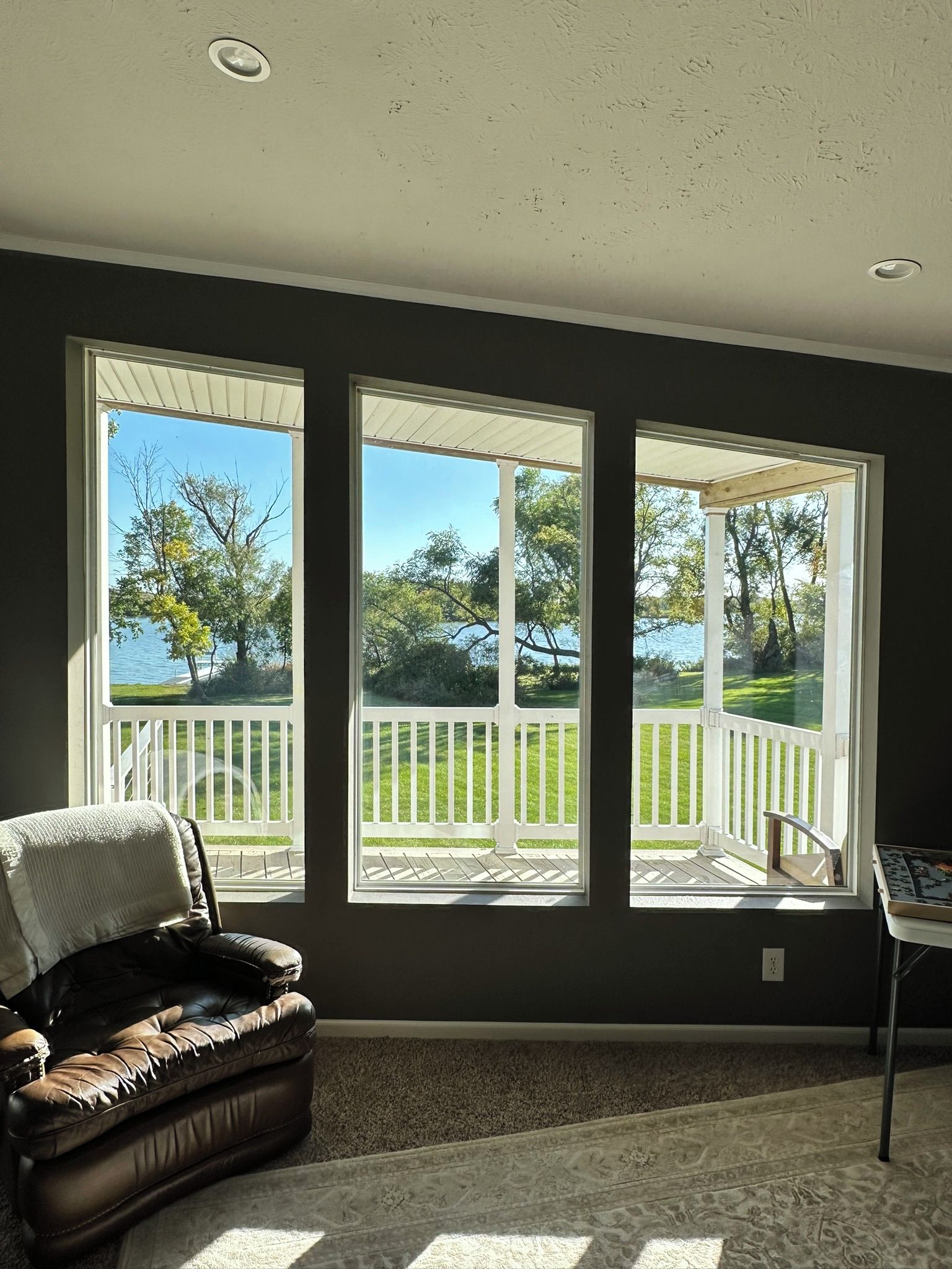 Quarto com vista para um deck e árvores, uma poltrona de couro e uma mesa com um jogo de tabuleiro.