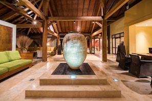A spacious lobby with a large vase centerpiece, wooden beams, a green sofa, and modern seating. - Waterfront villa on the lagoon, 2 bedrooms (Le François)