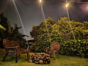Two wooden chairs and a stack of rocks in a garden at night. - D Monte Alto (ALTO BOQUETE)