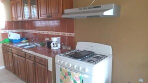 A kitchen with a gas stove, a coffee maker, and wooden cabinets. - D Monte Alto (ALTO BOQUETE)
