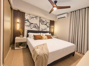 A modern bedroom with a bed, nightstands, a ceiling fan, and a marble wall. - Lovely 2-bedroom apartment with AC in vibrant Punta Cana (Punta Cana)