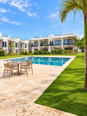 A modern hotel with a swimming pool, outdoor seating, and a well-maintained lawn. - Lovely 2-bedroom apartment with AC in vibrant Punta Cana (Punta Cana)