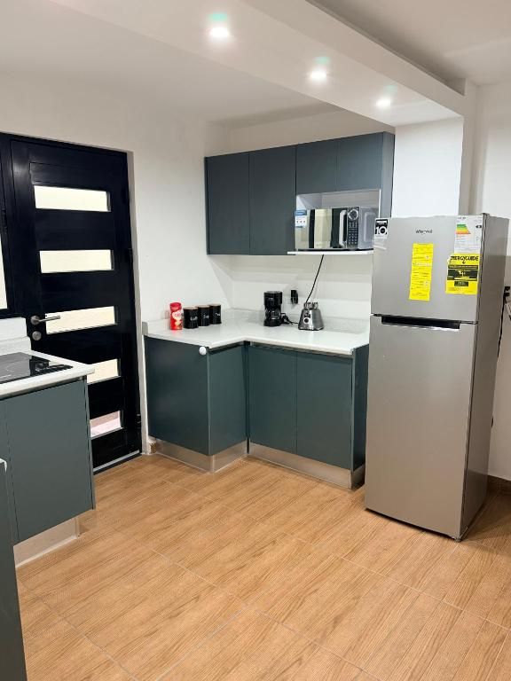 Una cocina moderna con armarios grises, una encimera blanca y un refrigerador de acero inoxidable.