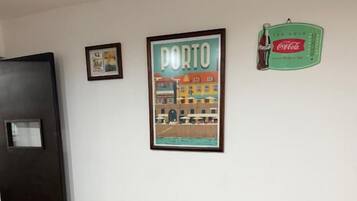 Un pasillo con un cuadro enmarcado de Oporto, una puerta y un cartel de Coca-Cola en la pared.