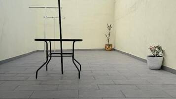 Un patio al aire libre con una mesa, un paraguas, una planta en maceta y una pared.