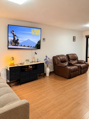 A living room with a flat-screen TV, a sofa, a desk with drawers, a vase with flowers, and a fireplace. - Las Minervas residencias (Monterrey)