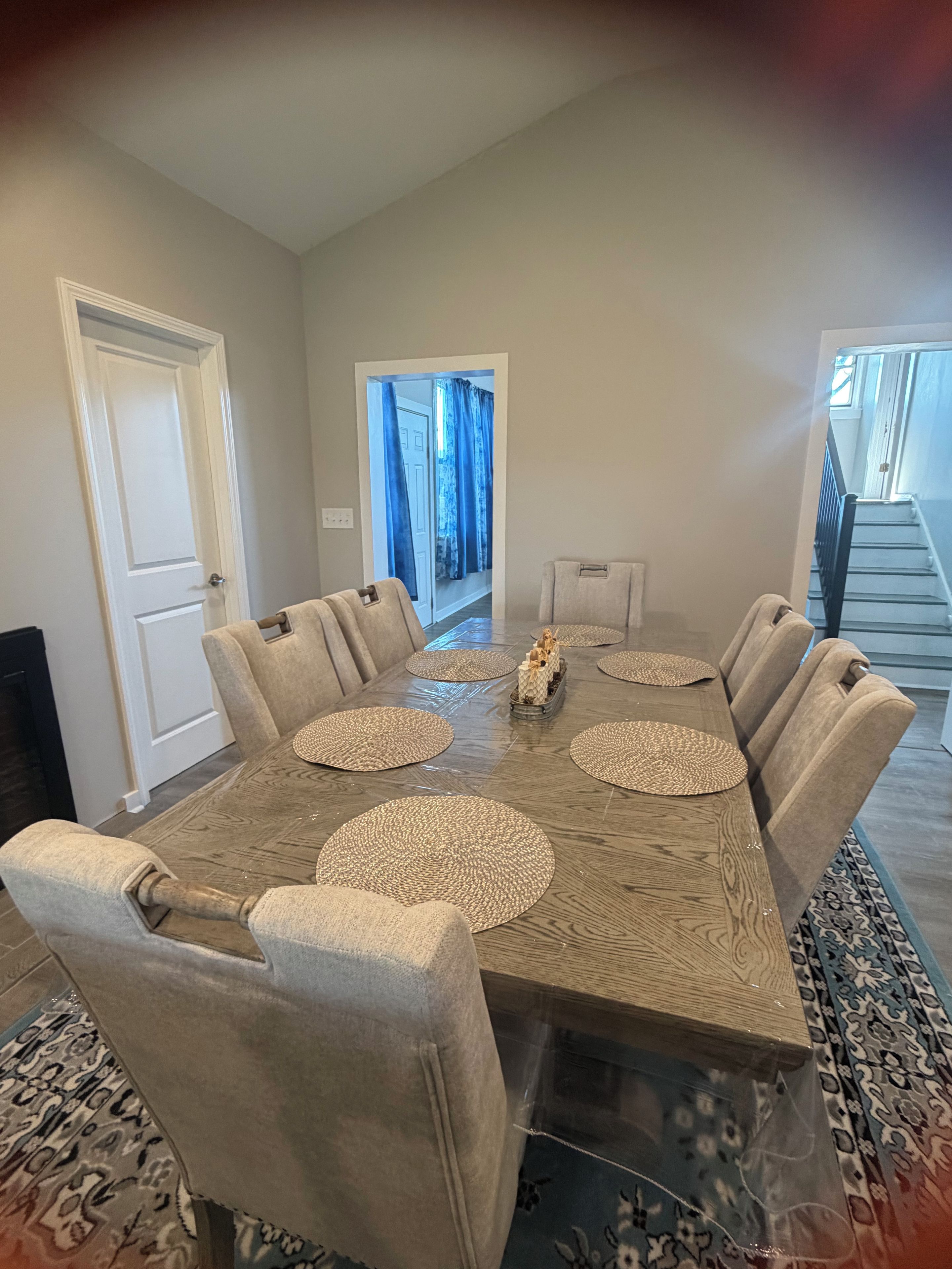 A dining room with a large wooden table, six upholstered chairs, and a central decorative piece.