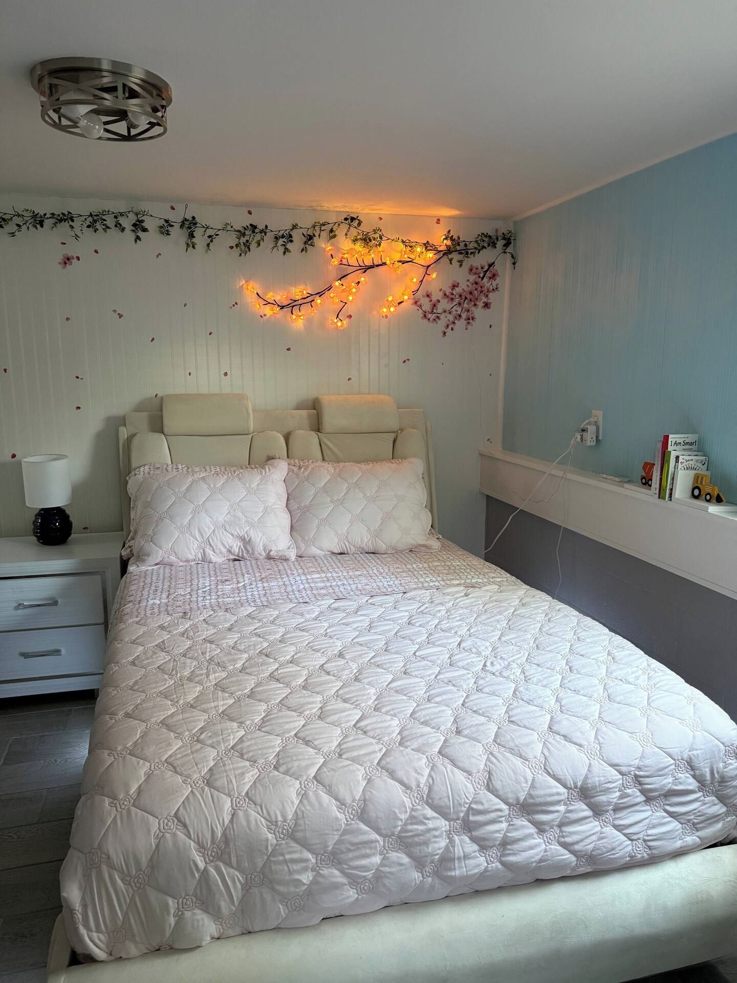 Een slaapkamer met een bed, nachtkastjes, een lamp en een wandlamp.