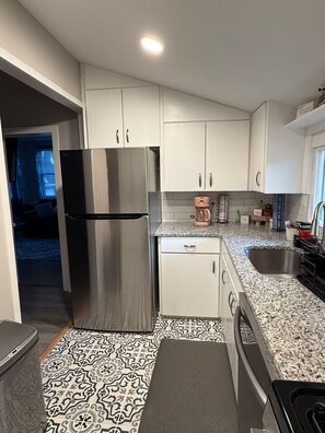 A modern kitchen with stainless steel appliances, white cabinets, and patterned floor tiles. - Nalls Retreat (Radcliff)