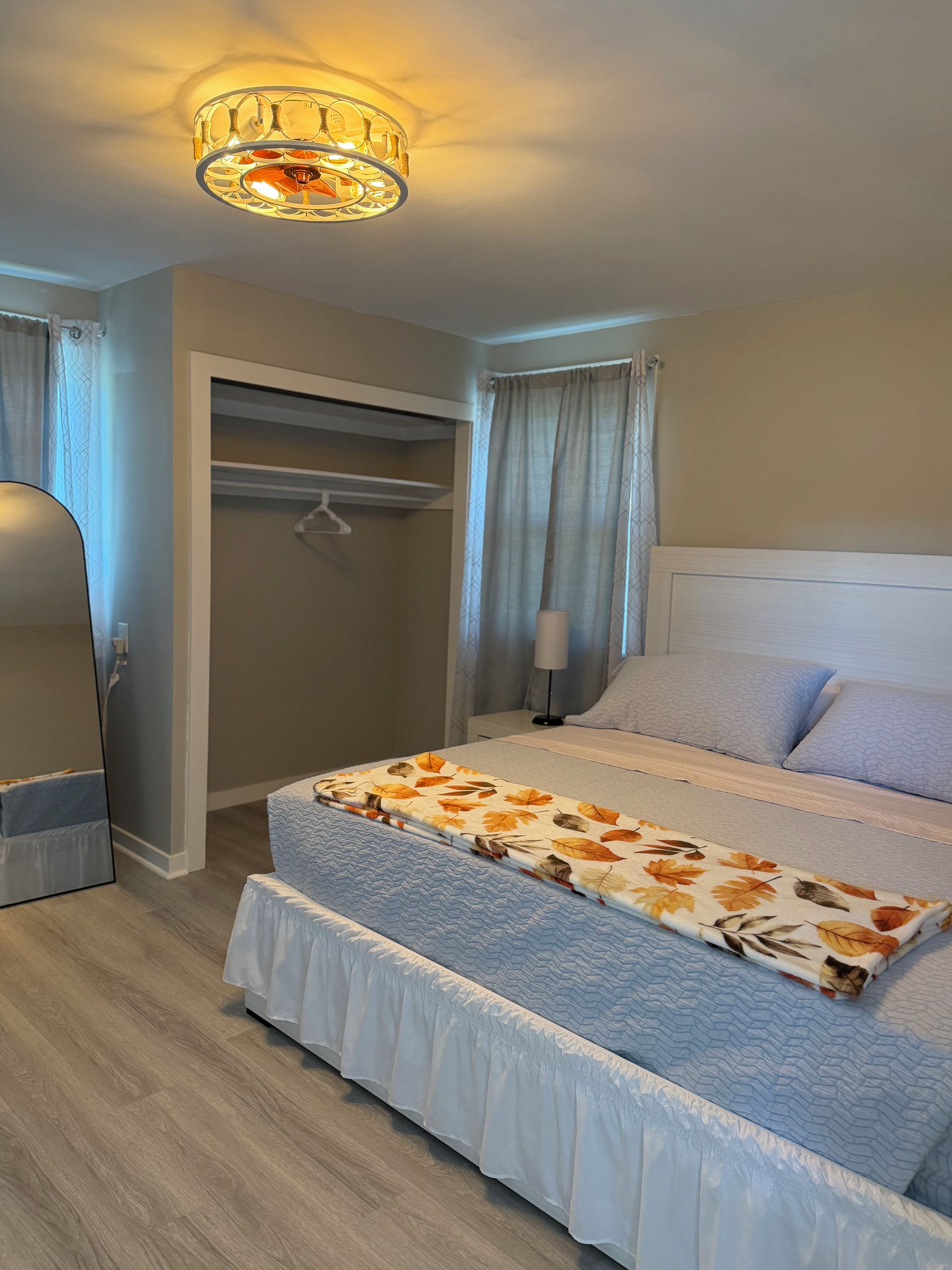 Ein Schlafzimmer mit einem Bett, einem Nachttisch, einer Lampe, einem Kleiderschrank und einer Deckenleuchte.