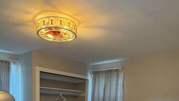 Ein Schlafzimmer mit einem Bett, einem Nachttisch, einer Lampe, einem Kleiderschrank und einer Deckenleuchte.