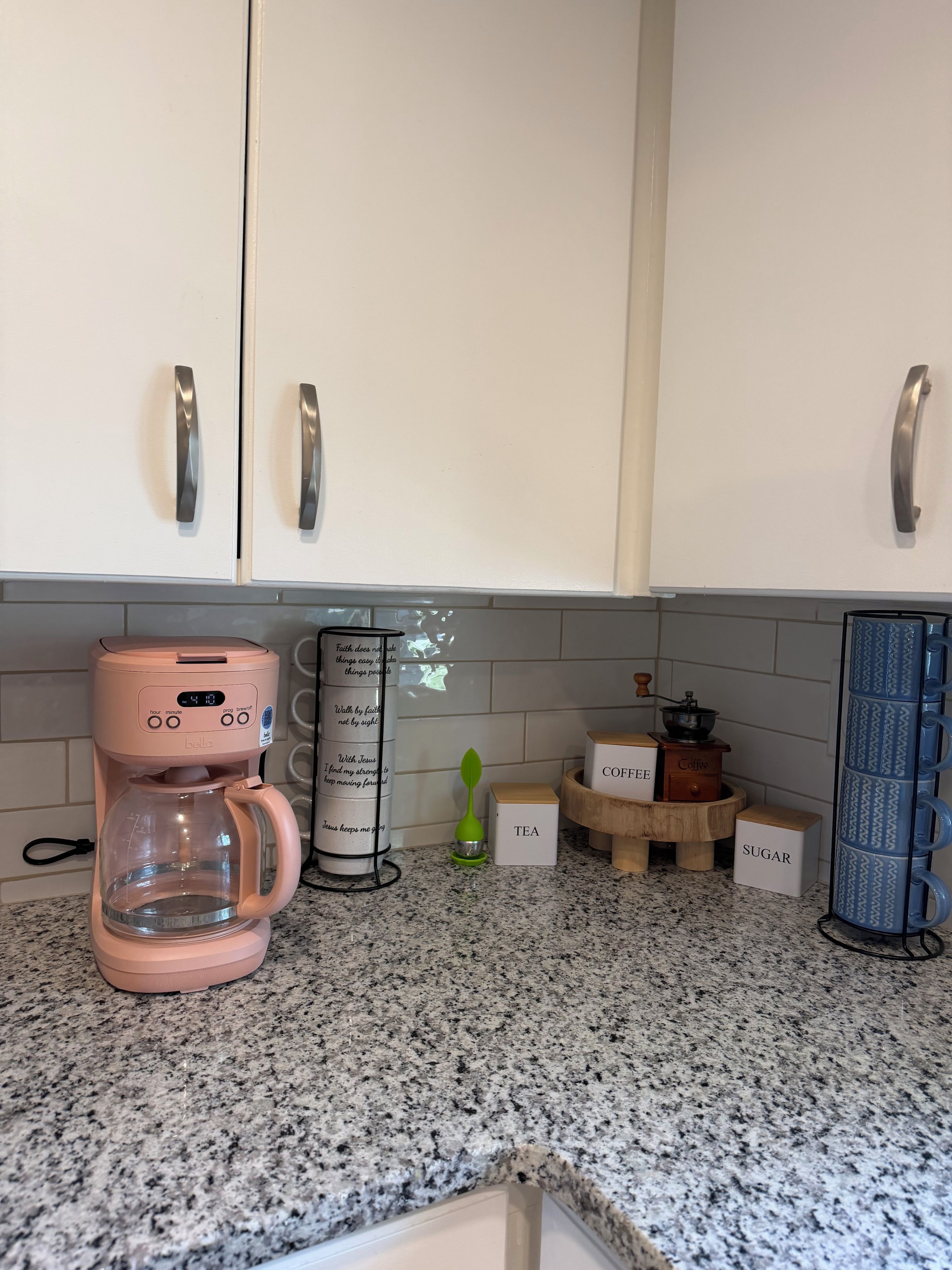 Una cocina con cafetera, hervidor y recipientes etiquetados como 'café', 'té' y 'azúcar'.
