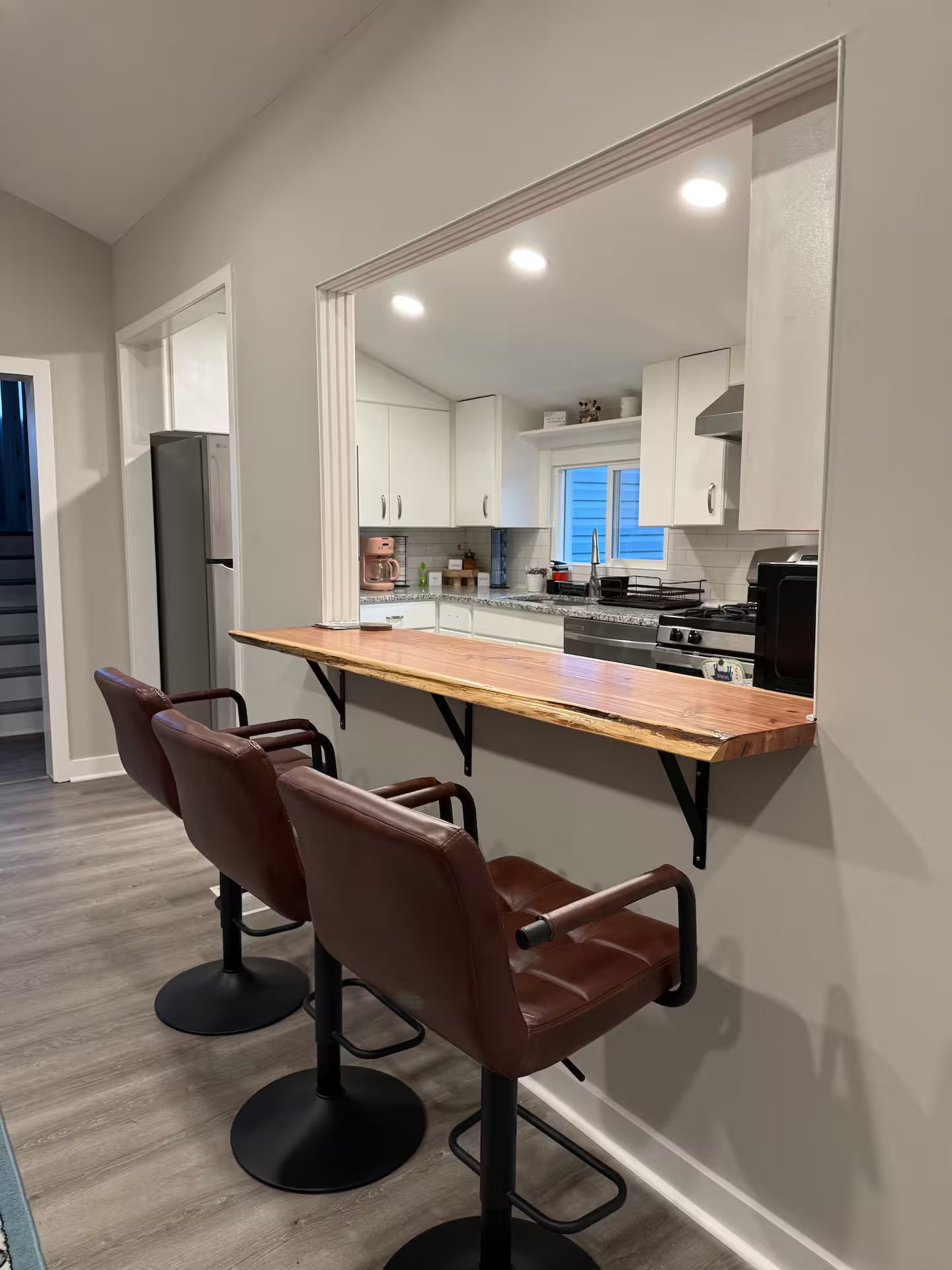 Una cocina moderna con armarios blancos, encimera de madera y extractor de acero inoxidable.