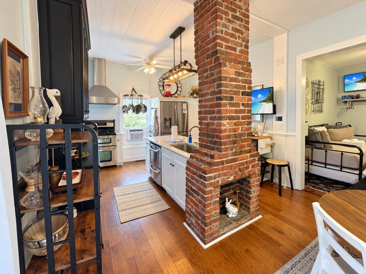Una cocina moderna con chimenea de ladrillo, suelo de madera y zona de comedor con mesa y sillas.
