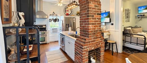 Una cocina moderna con chimenea de ladrillo, suelo de madera y zona de comedor con mesa y sillas.