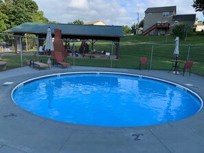 A swimming pool with a covered patio area, lounge chairs, and a fenced yard. - Modern stay-near Fort Knox (Radcliff)