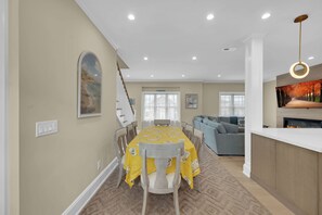 A dining area with a table set for four, a staircase, a living room with a sofa, and a fireplace. - Lavallette Beach House 4BR/3BA - Perfect for Fall Getaways! - Sleeps 10 - Unit B (Lavallette)