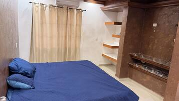 A bedroom with a bed, a wardrobe, and a built-in shelf unit.