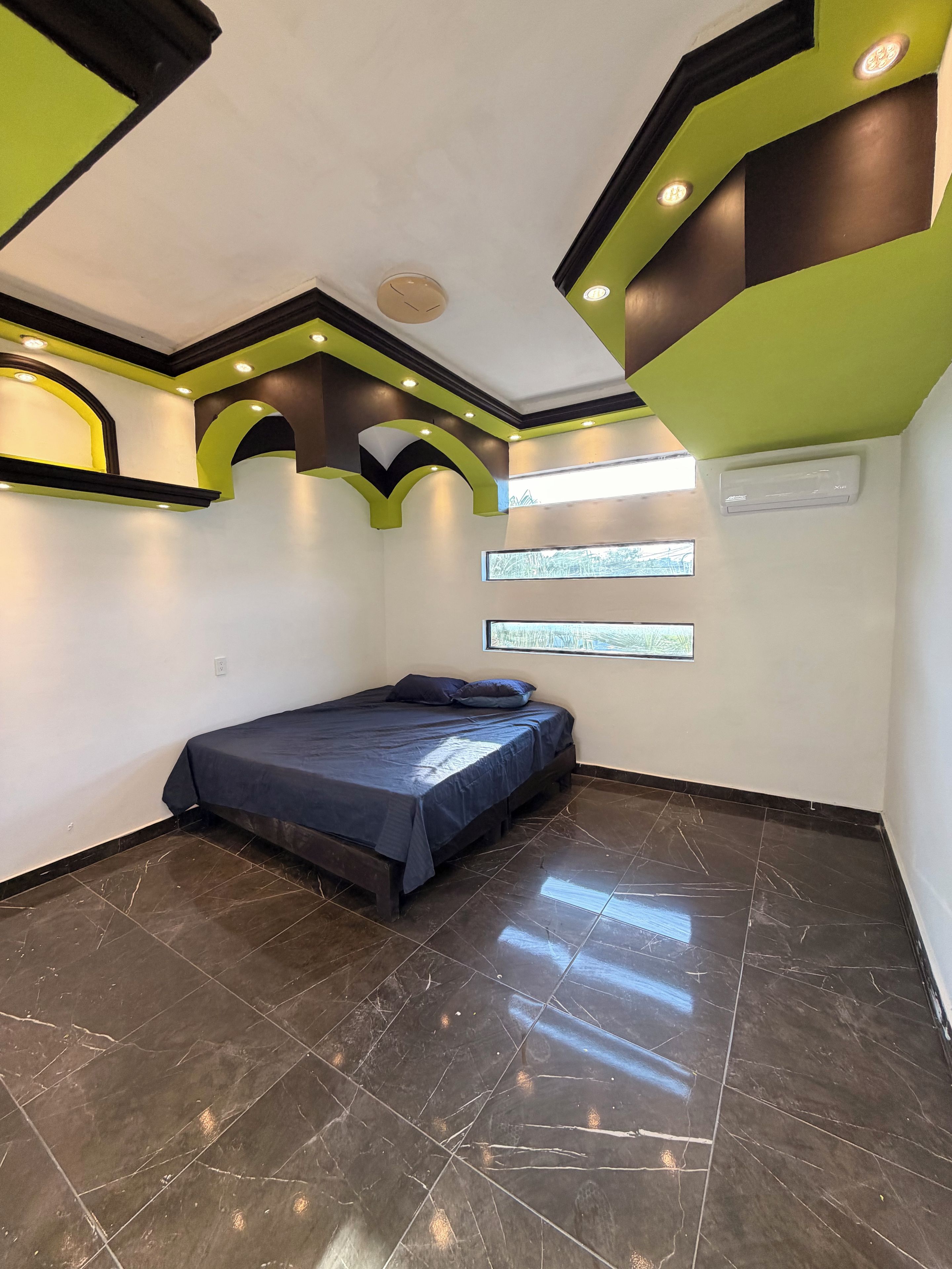 Une chambre à coucher avec un lit, une fenêtre et un plafond doté d’un éclairage encastré.