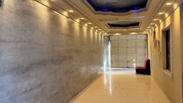 A corridor with a tiled floor, a red chair, and a garage door at the end.