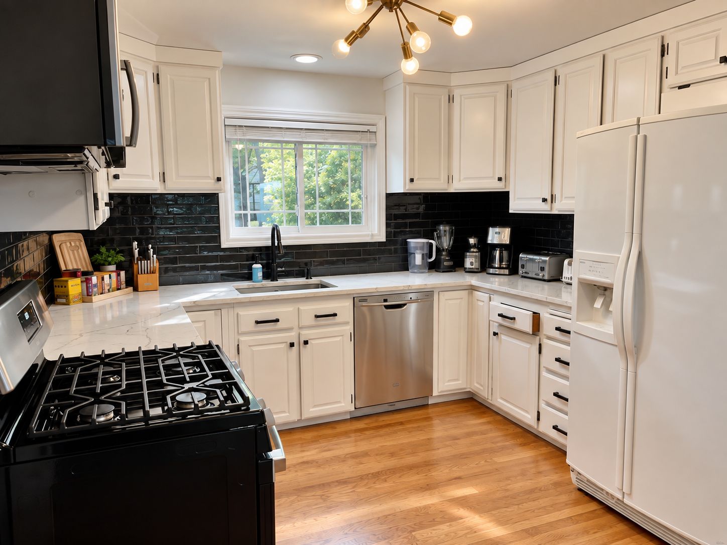 A modern kitchen with white cabinetry, a black stove, and a window with blinds.