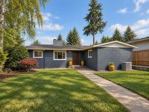 A residential house with a front yard, a driveway, and a wooden fence. - The Mercer Haven  (Mercer Island)