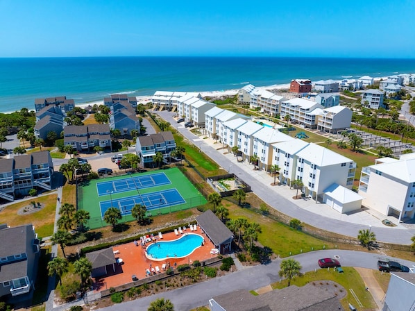 A coastal residential area with a tennis court, swimming pool, and beachfront views.