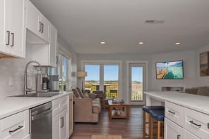 A modern kitchen with white cabinetry, a built-in oven, and a large window overlooking a balcony.