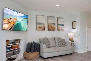 A living room with a sofa, a television, and wall art.