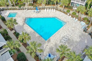 A large outdoor swimming pool with lounge chairs and umbrellas, surrounded by palm trees and a paved deck. - Barefoot Cottage A3 (Port St. Joe)