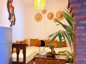 A room with a bed, a wooden coffee table with water bottles, a vase with flowers, and a wall-mounted clock. - Dar Lala Khadouj (Chefchaouen)