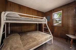 A bunk bed room with wooden walls, a window, and a small chair. - The Dockside Shores at Sommerdorf (West Branch)