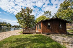 Una cabana de fusta amb terrassa, situada al costat d'un llac amb un moll al fons.