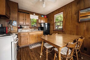 A kitchen with wooden cabinets, a dining table, and chairs. - The Dockside Shores at Sommerdorf (West Branch)