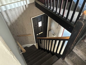 Una escalera con barandilla negra y pared blanca.