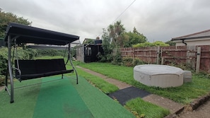 Un patio trasero con un columpio, un jacuzzi y una zona delimitada por una cerca.