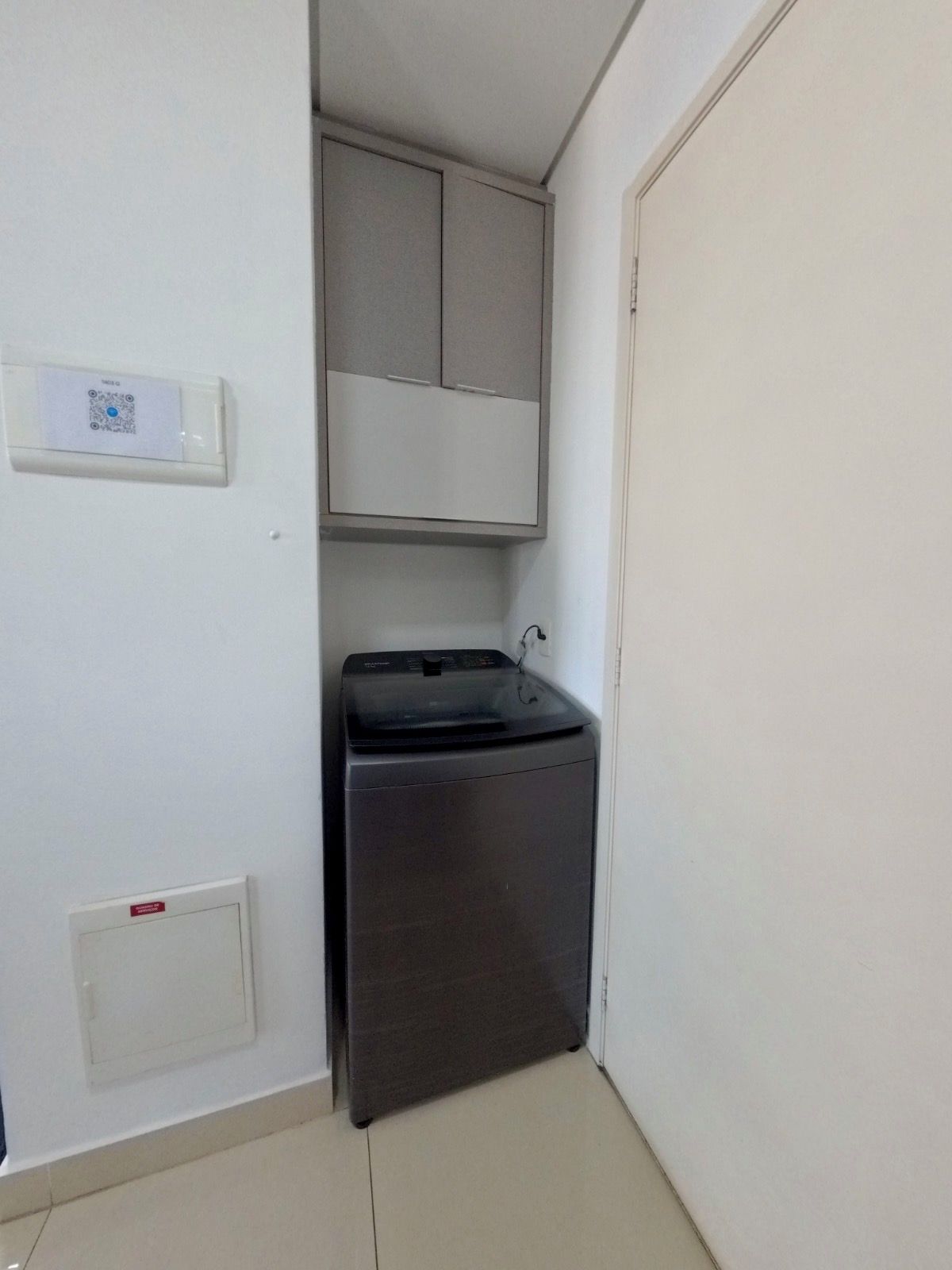 Une petite buanderie équipée d’un lave-linge et d’un meuble de rangement.