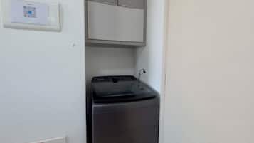 Une petite buanderie équipée d’un lave-linge et d’un meuble de rangement.