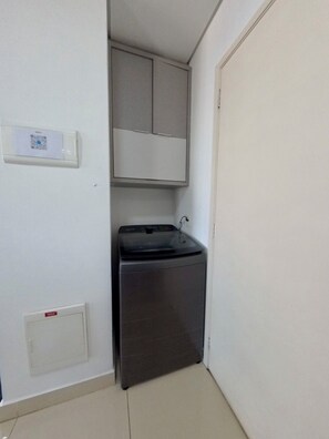 Une petite buanderie équipée d’un lave-linge et d’un meuble de rangement.