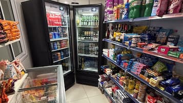 Un rayon d’épicerie où les étagères sont remplies de divers produits, notamment des boissons, des en-cas et des articles ménagers.