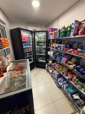 Un rayon d’épicerie où les étagères sont remplies de divers produits, notamment des boissons, des en-cas et des articles ménagers.