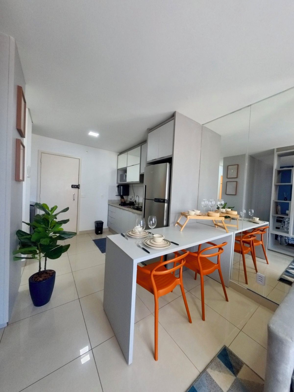 Une cuisine moderne avec un îlot central, des chaises orange et une table à manger pour quatre personnes.