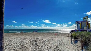Una playa con una torre de salvavidas, arena y océano.