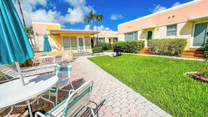 A hotel courtyard with outdoor seating, a well-maintained lawn, and a clear sky. - Cozy Beach Studio Pool and Free Parking (Hollywood)