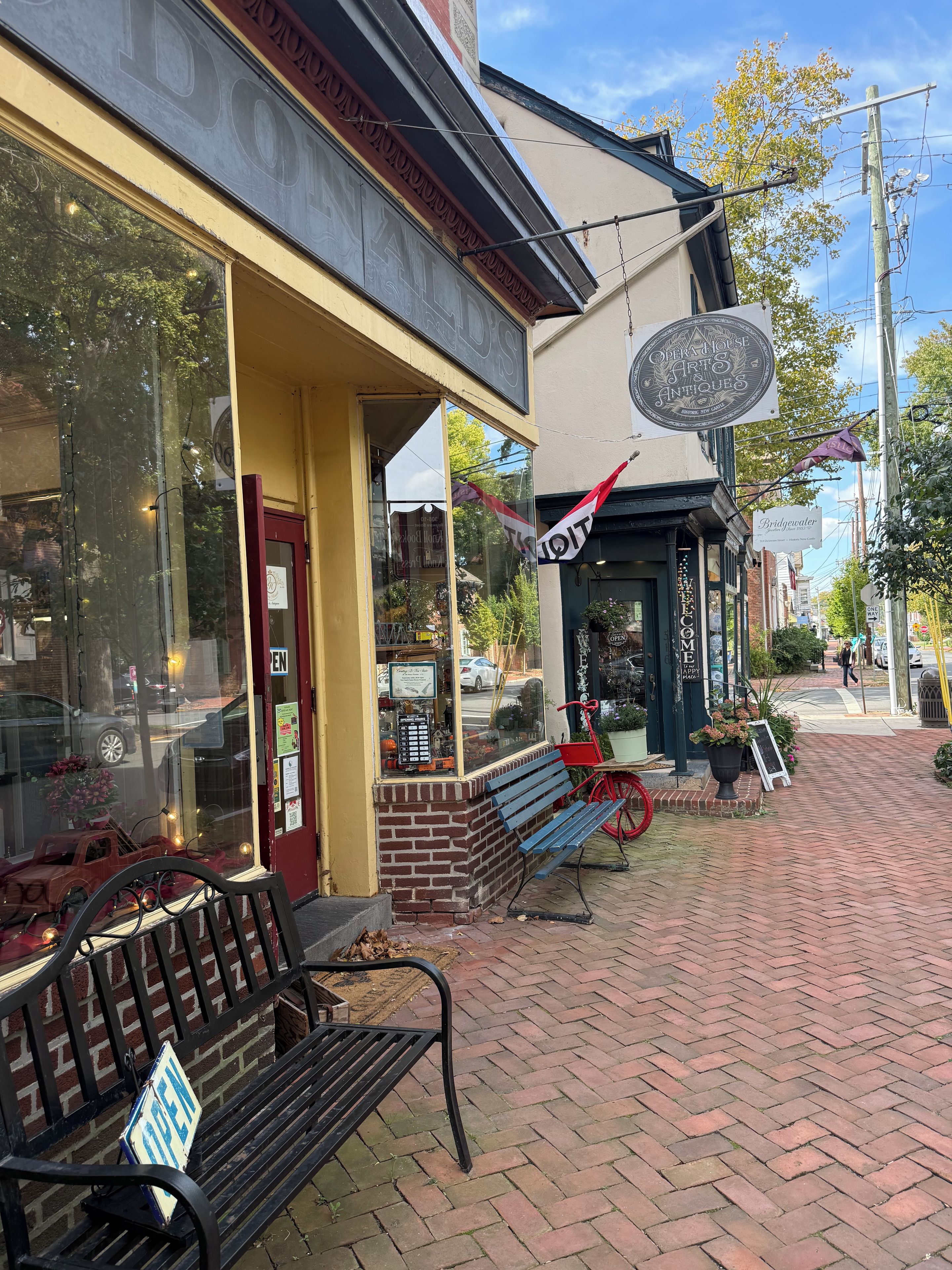 A storefront with a brick facade, a red bench, and a bicycle.