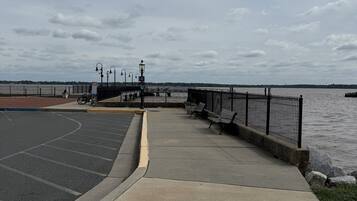 A waterfront promenade with a paved walkway, benches, and a bike rack.