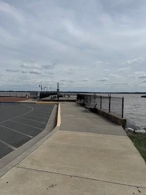 A waterfront promenade with a paved walkway, benches, and a bike rack.